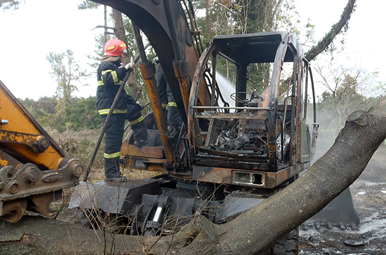 작업을 하던 굴삭기가 불에 탔다. 소방관들이 잔불 정리를 하고 있다.