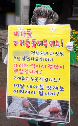 오토바이 사고로 한쪽 다리를 잃은 A군의
부모 C씨가 제주시내 모 병원 앞에서 1인 시
위를 벌이고 있다.