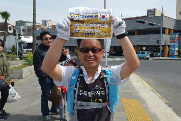 이지훈 사무관이 마라톤을 하면서 '청렴한 세상, 사람과 자연이 공존하는 제주'라는 글이 적힌 피켓을 들어 보이고 있다.